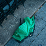 Green umbrella made from environmentally-friendly non-recyclable waste. Will possibly biodegrade by the time it takes humans to become civilized.