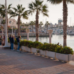 Three young boys water some flowers near a boat dock and a few expensive restaurants. I tried to send this picture off as an advertisement for the Gap but I was refused because one of the boy's Gap jeans were from last season.